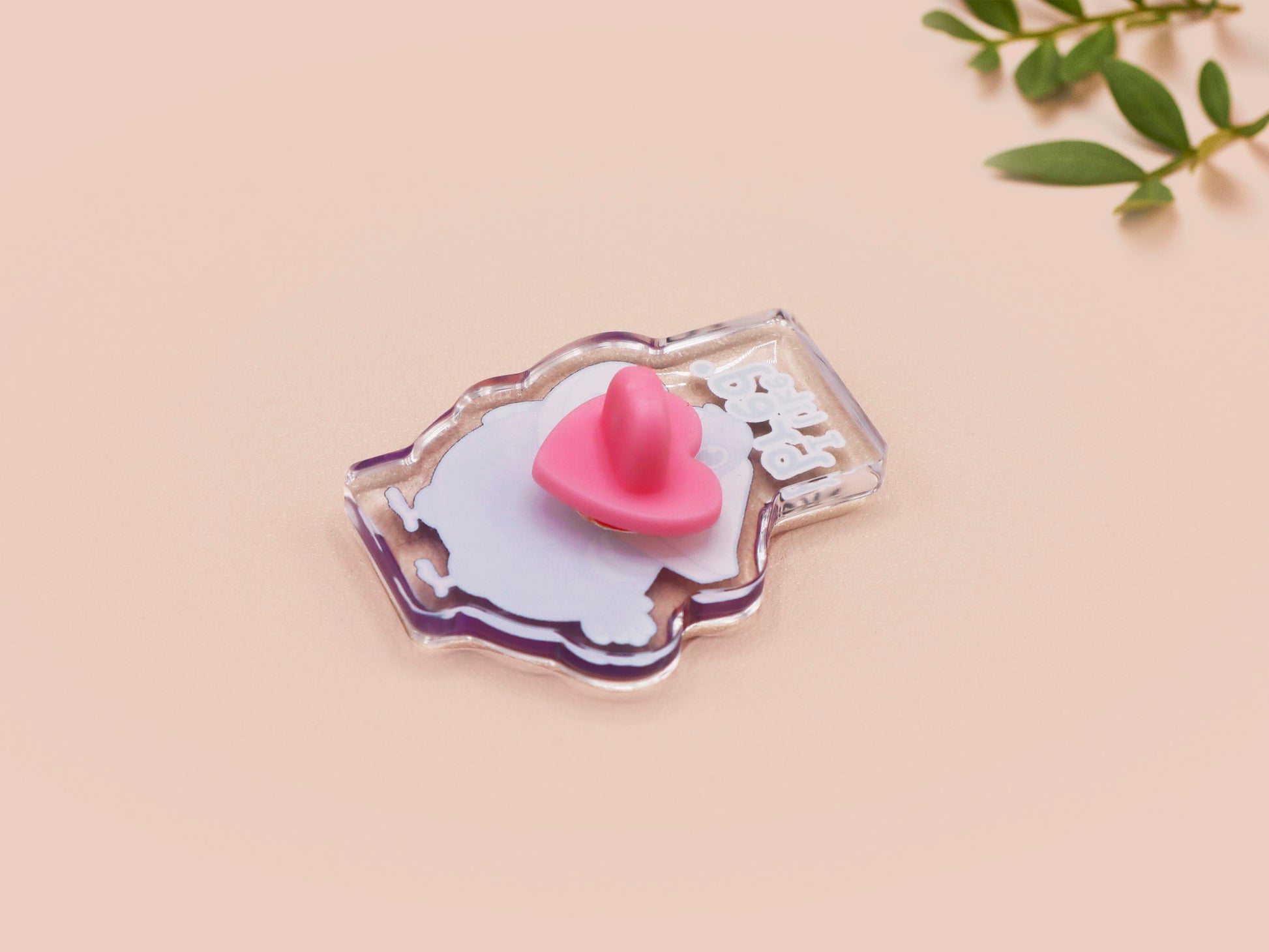 A transparent acrylic pin badge with a pink heart-shaped pin-back clutch. The design of the pin badge is a cute cartoon pigeon with a slice of bread around it's neck with the quote I like bred.