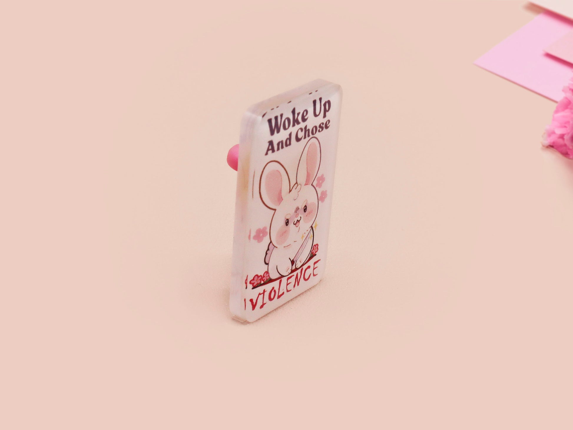Clear acrylic pin badge with pink heart-shaped rubber pin back clasp. The design of the pin badge is a cute cartoon chibi white rabbit with the quote Woke Up And Chose Violence.