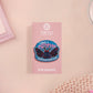 Clear acrylic pin badge with pink heart-shaped rubber pin back clasp. The design of the pin badge is a cute cartoon chibi Mothman cryptid with the quote I believe in Mothman and Mothman believes in me.
