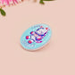 Clear acrylic pin badge with a pink heart-shaped rubber pin back clasp. The design of the pin badge is a cute chibi white cat in a retro astronaut suit with the quote I need space.