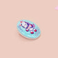 Clear acrylic pin badge with a pink heart-shaped rubber pin back clasp. The design of the pin badge is a cute chibi white cat in a retro astronaut suit with the quote I need space.