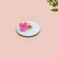 Clear acrylic pin badge with a pink heart-shaped rubber pin back clasp. The design of the pin badge is a cute chibi white cat in a retro astronaut suit with the quote I need space.