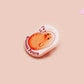 A clear acrylic pin badge with a pink heart-shaped pin back clasp. The design of the pin badge is of a cute chibi potato with the quote I'm a lil' stressed potato