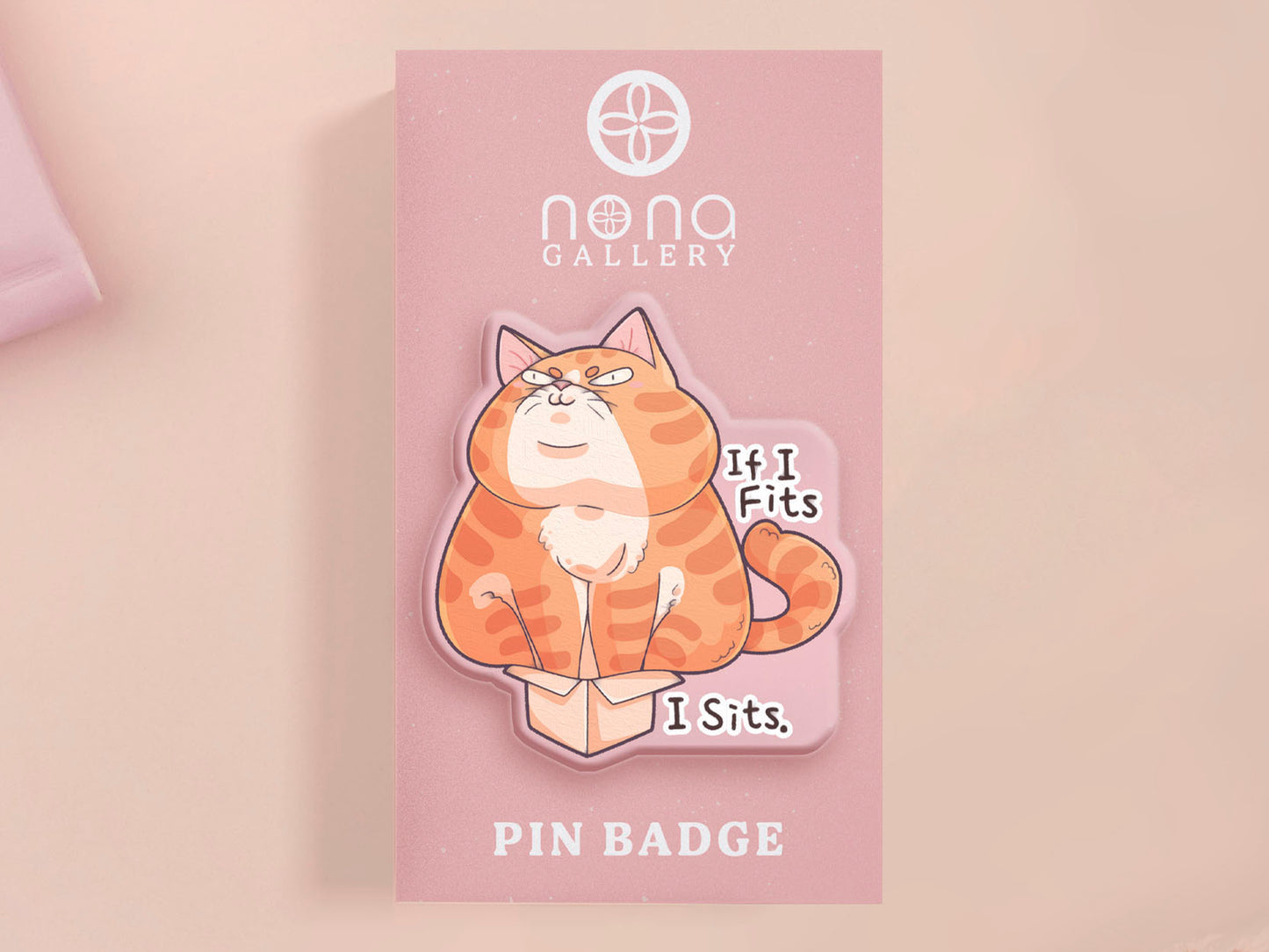 Clear acrylic pin badge with pin heart-shaped pin back clasp. The design of the pin badge is a cute cartoon ginger cat sat in a small cardboard box with the quote if I fits I sits.