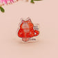 Clear acrylic pin badge with pin heart-shaped pin back clasp. The design of the pin badge is a cute cartoon ginger cat sat in a small cardboard box with the quote if I fits I sits.