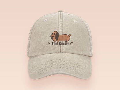 Vintage cream baseball cap with an embroidered design of a cute dachshund dog looking concerned and the quote "In This Economy?"