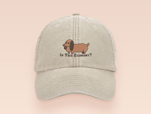 Vintage cream baseball cap with an embroidered design of a cute dachshund dog looking concerned and the quote "In This Economy?"