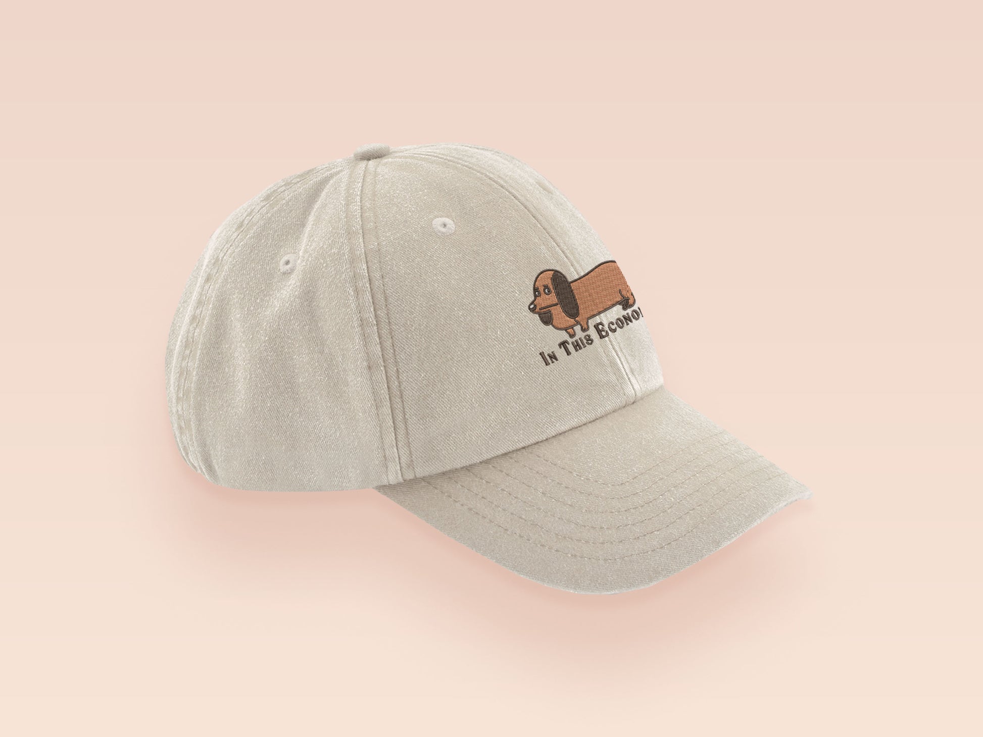 Vintage cream baseball cap with an embroidered design of a cute dachshund dog looking concerned and the quote "In This Economy?"