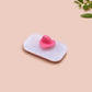 A clear acrylic pin badge with a pink heart-shaped pin back clasp. The design of the pin badge is of a cute chibi dachshund sausage dog with the quote in this economy?