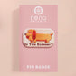 A clear acrylic pin badge with a pink heart-shaped pin back clasp. The design of the pin badge is of a cute chibi dachshund sausage dog with the quote in this economy?