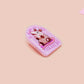 A clear acrylic pin badge with a pink heart-shaped pin back clasp. The design of the pin badge is of a cute screaming possum with the quote is it me am I the drama?