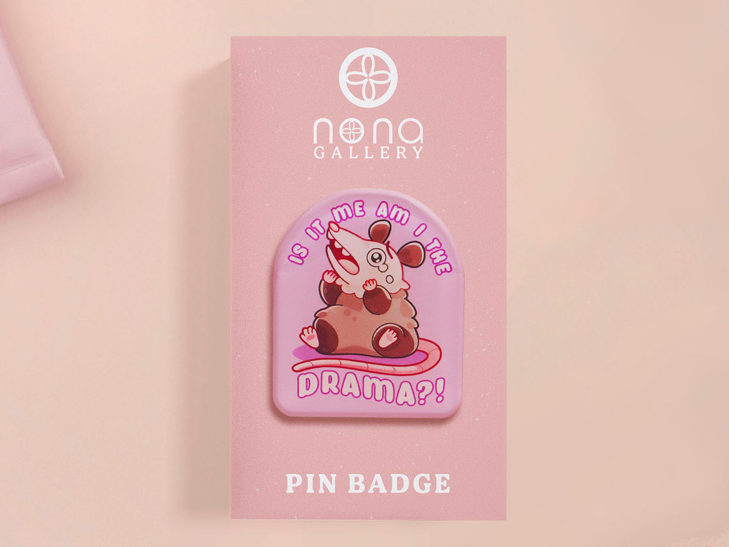 A clear acrylic pin badge with a pink heart-shaped pin back clasp. The design of the pin badge is of a cute screaming possum with the quote is it me am I the drama?