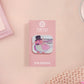 A clear acrylic pin badge with a pink heart-shaped pin back clasp. The design of the pin badge is of a cute chibi pigeon wearing a top hat with the quoteit's called fashion susan