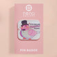 A clear acrylic pin badge with a pink heart-shaped pin back clasp. The design of the pin badge is of a cute chibi pigeon wearing a top hat with the quoteit's called fashion susan