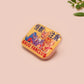 A clear acrylic pin badge with a pink heart-shaped pin back clasp. The design of the pin badge is of a cute chibi blue godzilla like kaiju mothra and King Ghidorah destroying a city with the quote kaiju fanclub and kaiju warning in japanese kanji
