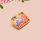 A clear acrylic pin badge with a pink heart-shaped pin back clasp. The design of the pin badge is of a cute chibi blue godzilla like kaiju mothra and King Ghidorah destroying a city with the quote kaiju fanclub and kaiju warning in japanese kanji