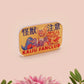 A clear acrylic pin badge with a pink heart-shaped pin back clasp. The design of the pin badge is of a cute chibi blue godzilla like kaiju mothra and King Ghidorah destroying a city with the quote kaiju fanclub and kaiju warning in japanese kanji