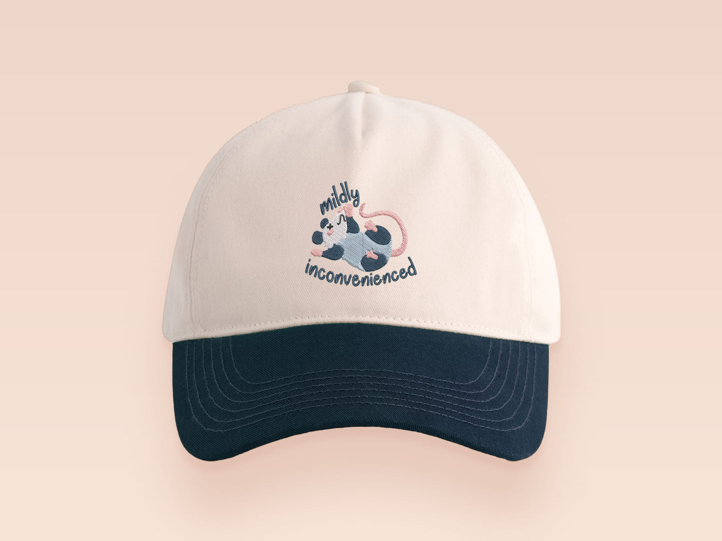 Vintage style truckers baseball cap with a contrast cream and navy peak design with an embroidered possum playing dead and the quote mildly inconveninced 