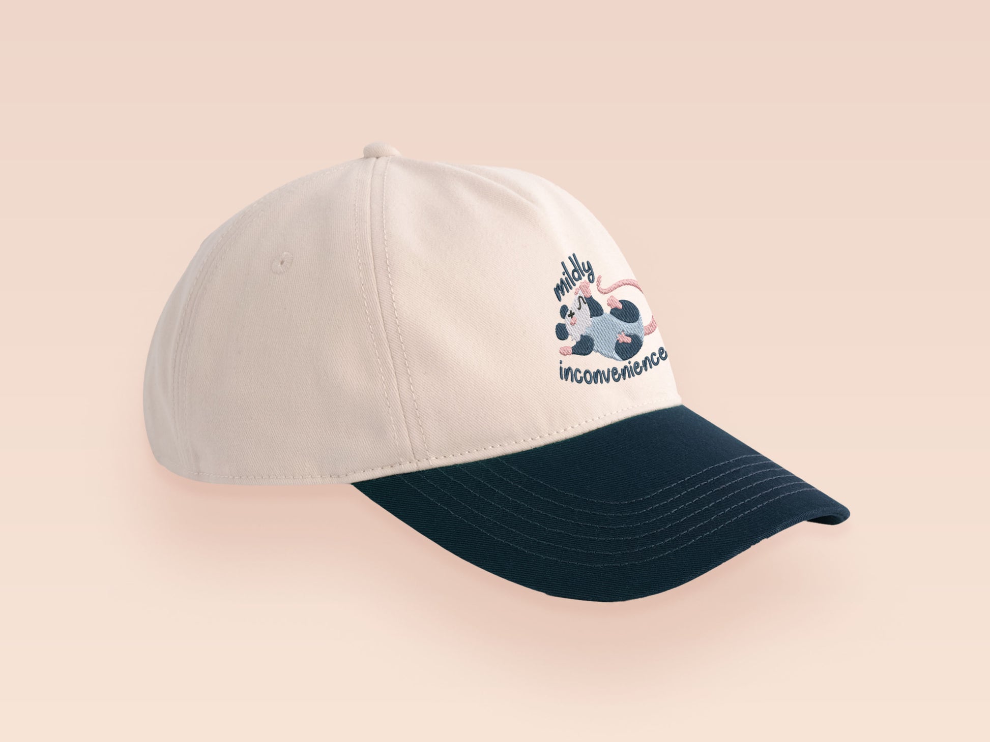 Vintage style truckers baseball cap with a contrast cream and navy peak design with an embroidered possum playing dead and the quote mildly inconveninced 