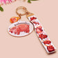 Acrylic keychain with a large charm of the fat angry pygmy hippo being picked up, a smaller charm of a cute baby hippo with the name Moo Deng in Thai and a matching mini lanyard of the pygmy hippo in multiple cute poses and expressions.
