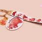 Acrylic keychain with a large charm of the fat angry pygmy hippo being picked up, a smaller charm of a cute baby hippo with the name Moo Deng in Thai and a matching mini lanyard of the pygmy hippo in multiple cute poses and expressions.