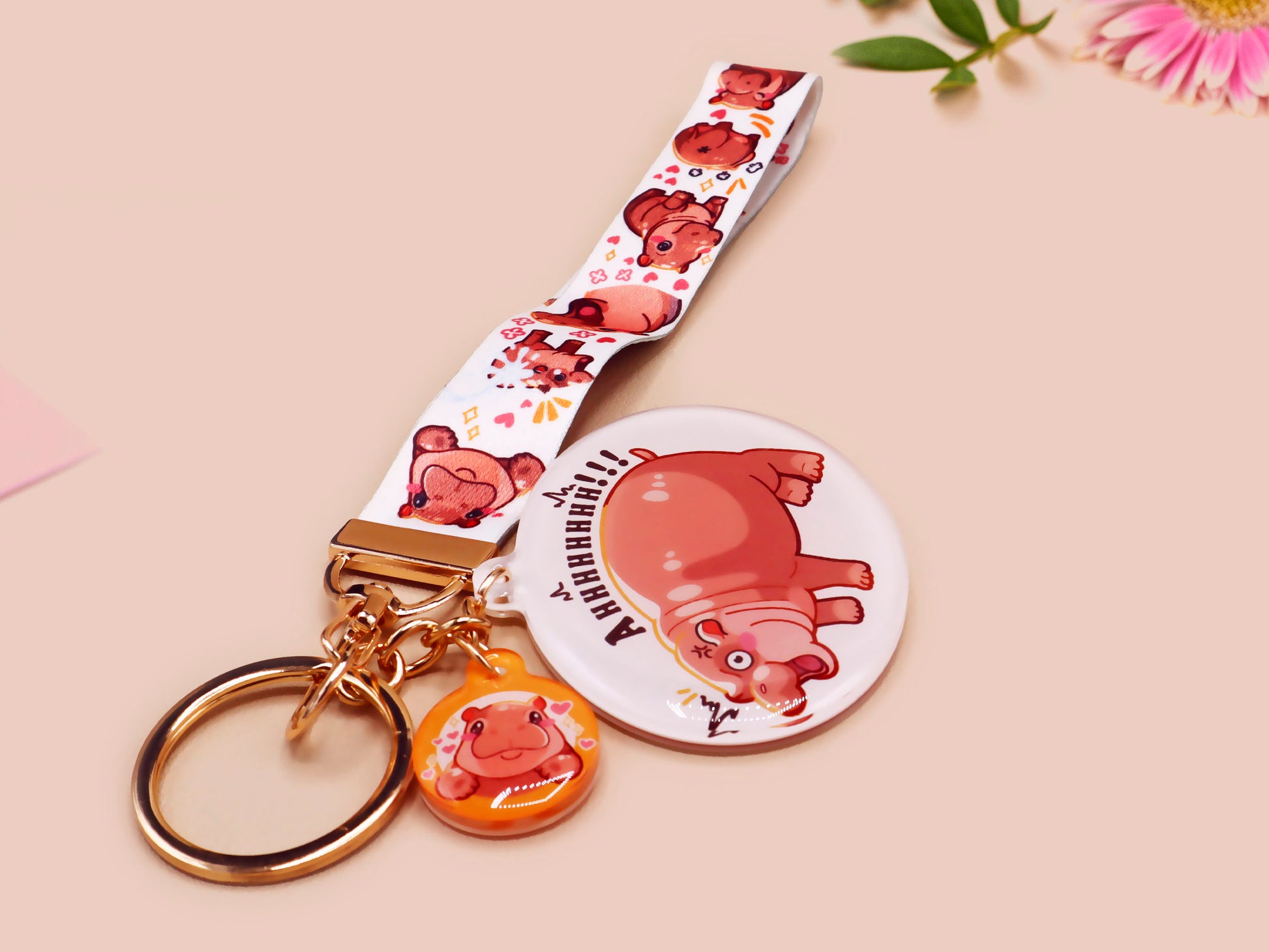 Acrylic keychain with a large charm of the fat angry pygmy hippo being picked up, a smaller charm of a cute baby hippo with the name Moo Deng in Thai and a matching mini lanyard of the pygmy hippo in multiple cute poses and expressions.