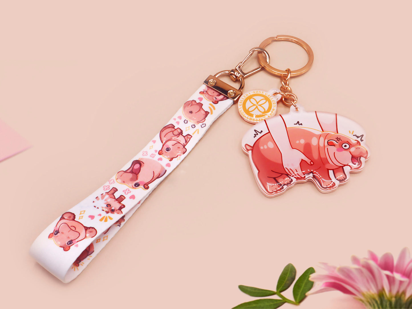 Acrylic keychain with a large charm of the fat angry pygmy hippo being picked up, a smaller charm of a cute baby hippo with the name Moo Deng in Thai and a matching mini lanyard of the pygmy hippo in multiple cute poses and expressions. 
