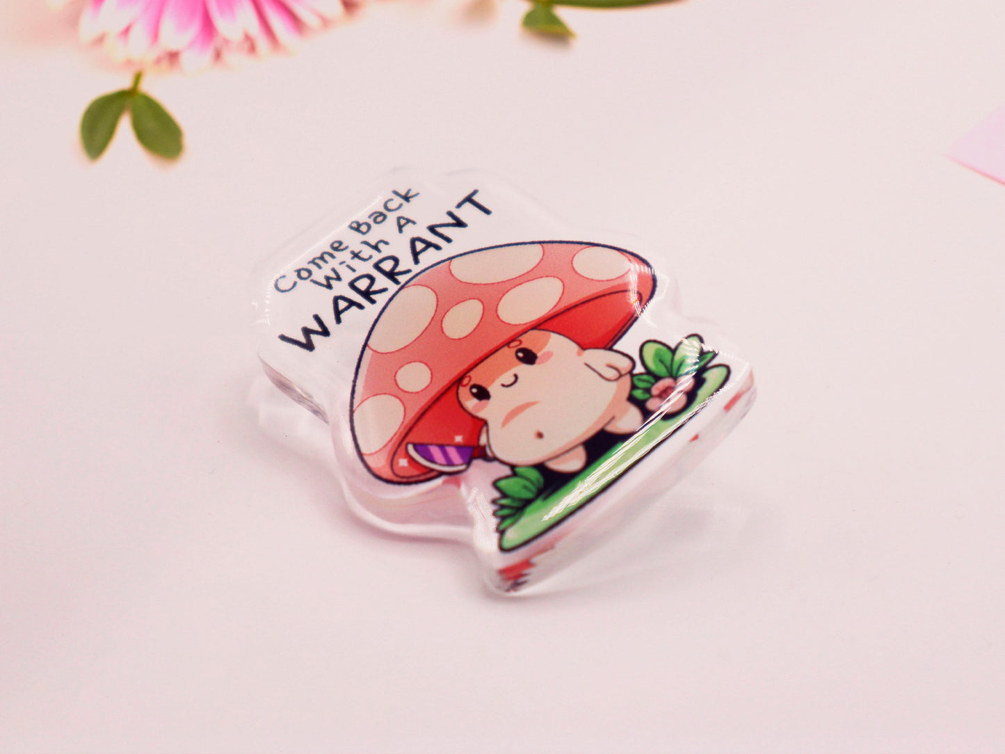 Acrylic Pin Badge of a smiling but ominous mushroom chibi with the quote come back with a warrant written above.