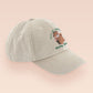 A cream baseball cap hat with an embroidered cute brown bear hiking with the quote out of breath walking society.