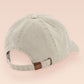 A cream baseball cap hat with an embroidered cute brown bear hiking with the quote out of breath walking society.