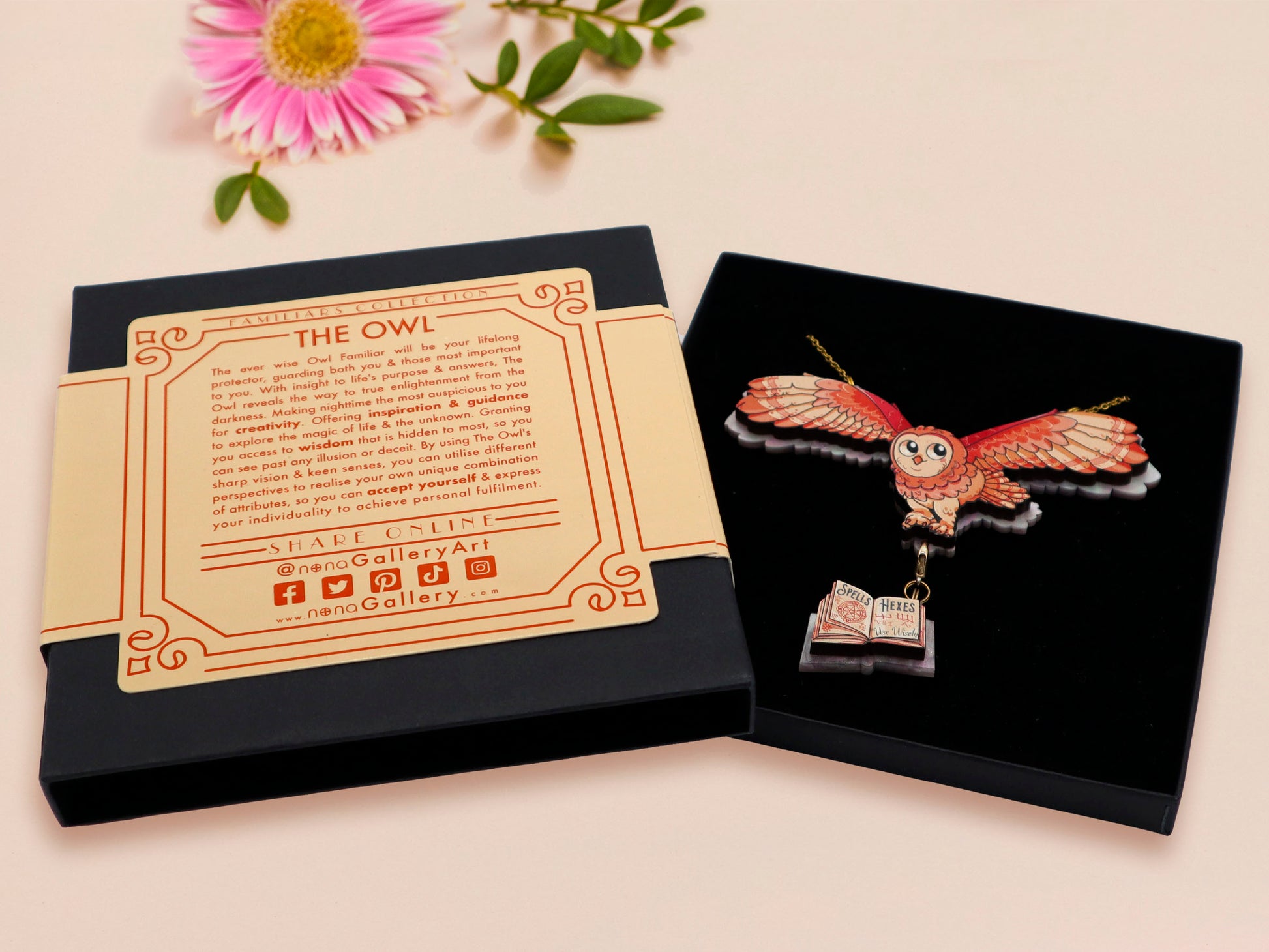 Mixed material handmade necklace of chibi cartoon flying barn owl with pearlescent wings carrying a removeable spell book charm, with a gold chain and black gift box with a yellow familiars collection gift sleeve.
