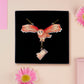 Mixed material handmade necklace of chibi cartoon flying barn owl with pearlescent wings carrying a removeable spell book charm, with a gold chain and black gift box.