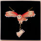 Mixed material handmade necklace of chibi cartoon flying barn owl with pearlescent wings carrying a removeable spell book charm, with a gold chain and black gift box.