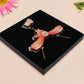 Mixed material handmade necklace of chibi cartoon flying barn owl with pearlescent wings carrying a removeable spell book charm, with a gold chain and black gift box.