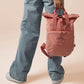 Pink roll top twin handle backpack with an embroided design of cute crying pig and the quote please do not percive me
