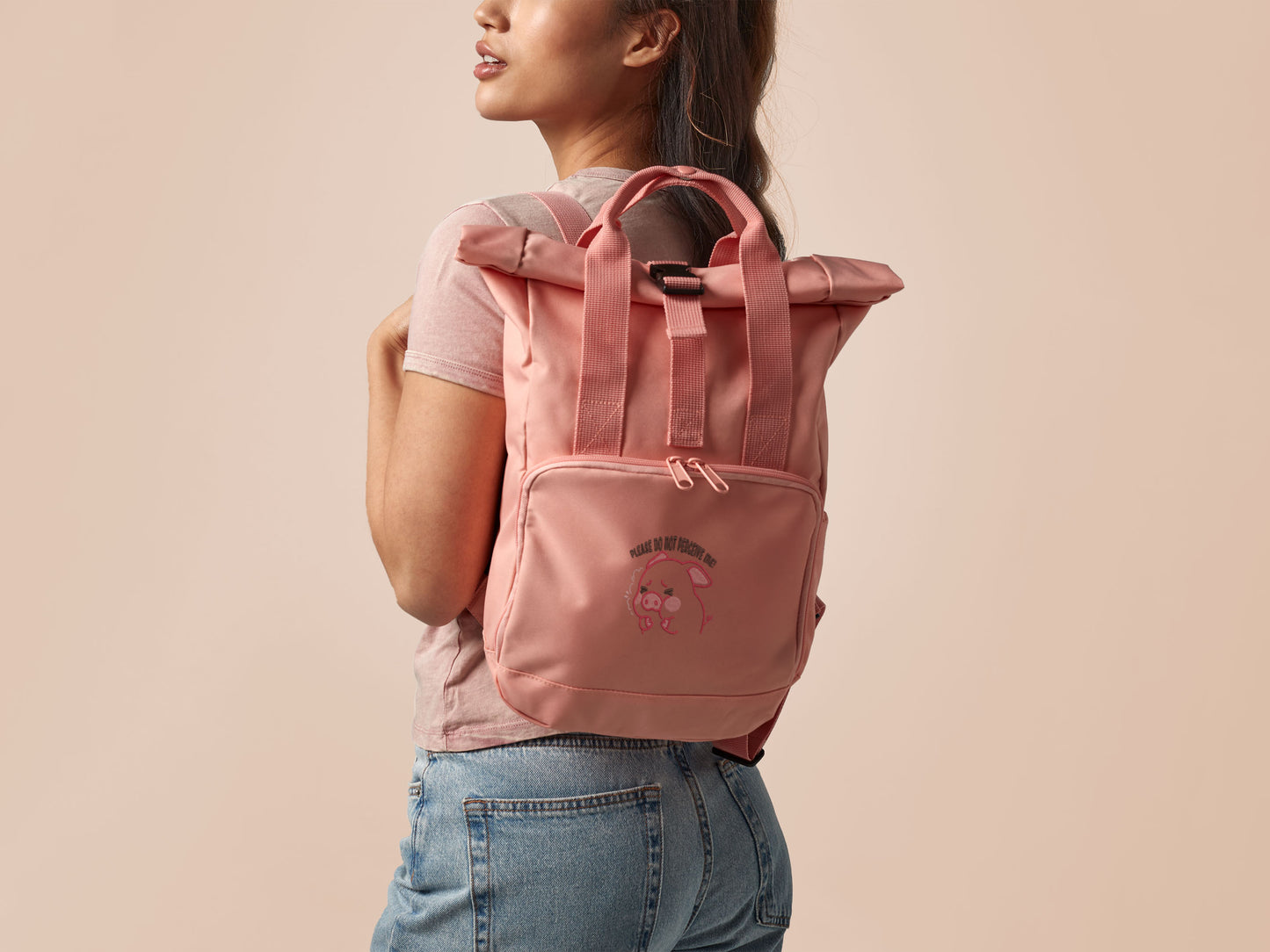 Pink roll top twin handle backpack with an embroided design of cute crying pig and the quote please do not percive me