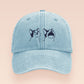 A blue baseball cap hat with an embroidered cute blue Popcat meme cat design.