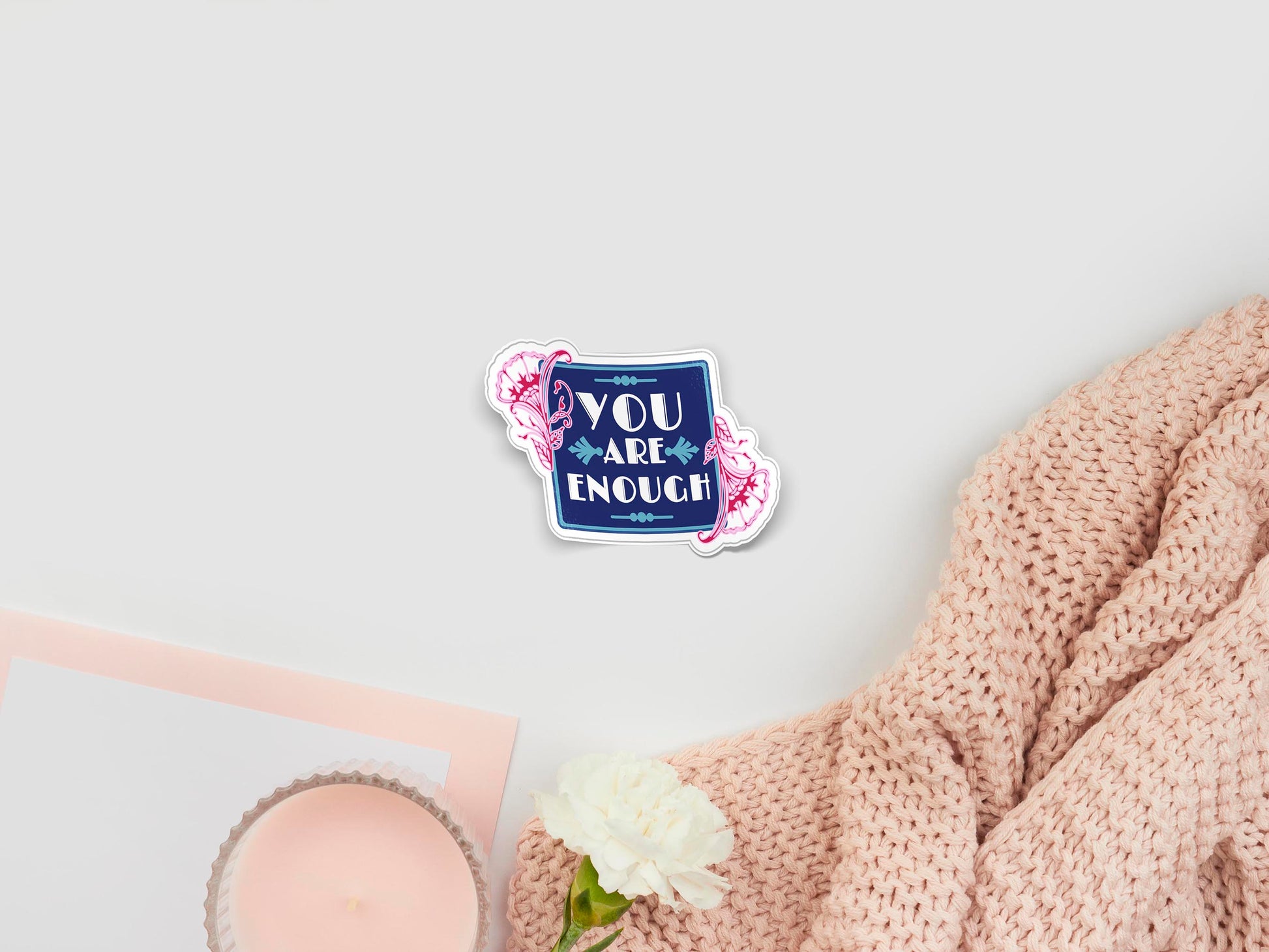 Large sticker of digital illustration cartoon of a blue square frame with pink floral accents and the text You Are Enough written in white font placed in the centre of the design