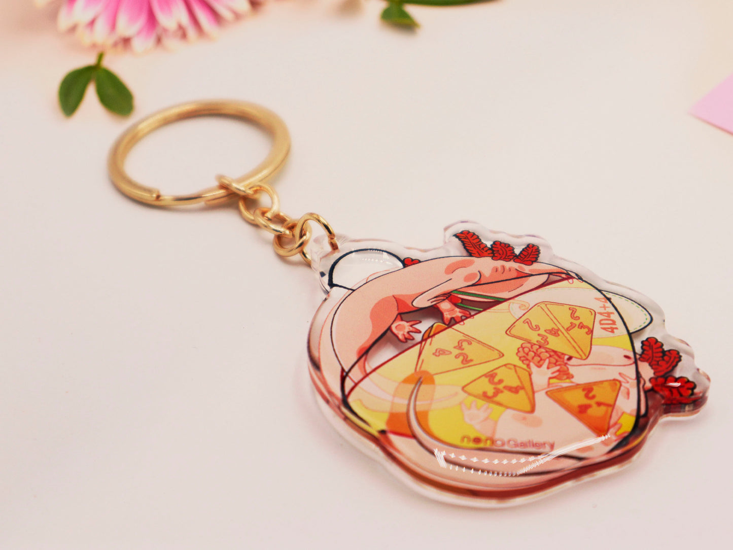 Clear acrylic double sided gold clasp keychain with a cartoon illustrated design of two pink axolotls on a potion bottle labelled health +hp and with a yellow liquid and four orange d4 dice inside.