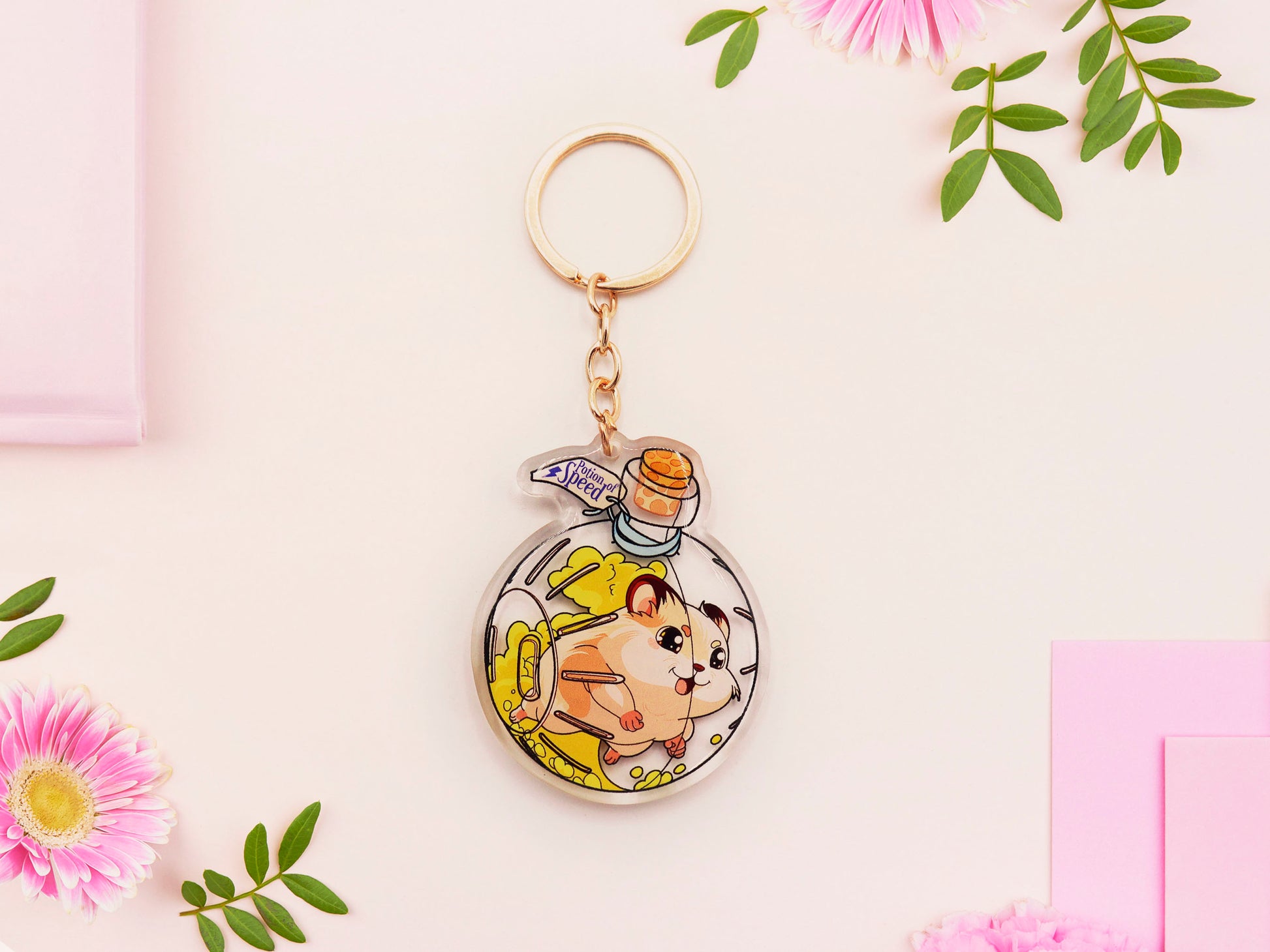 Double sided epoxy keychain with golden clasp of a happy Russian dwarf hamster running in a hamster ball shaped potion bottle labelled potion of speed