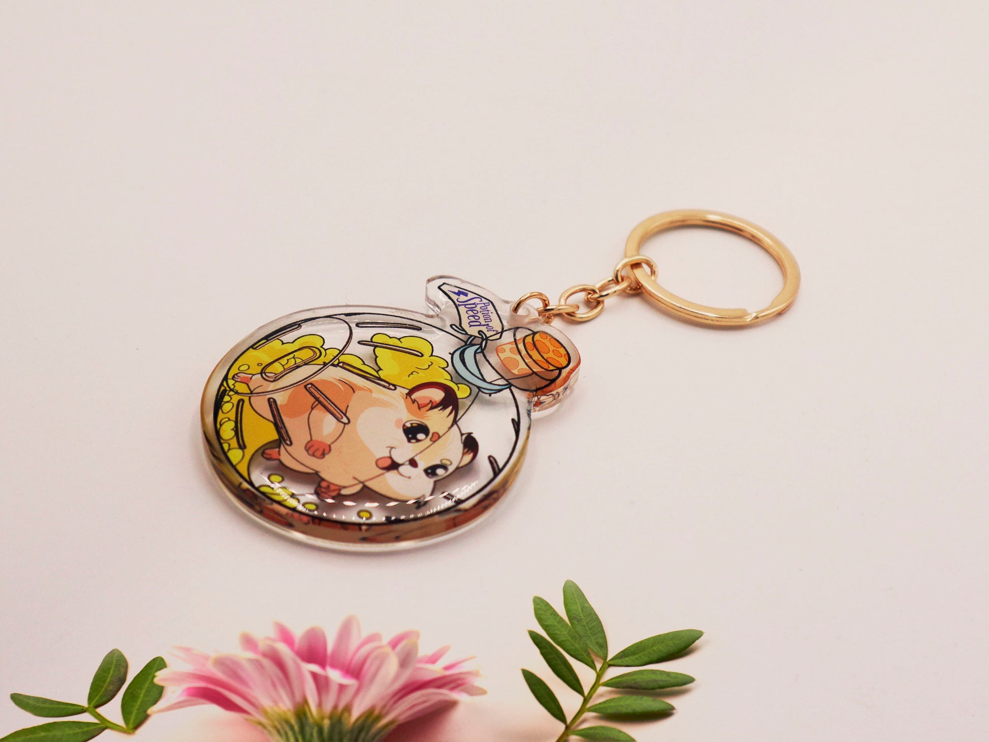 Double sided epoxy keychain with golden clasp of a happy Russian dwarf hamster running in a hamster ball shaped potion bottle labelled potion of speed