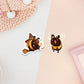 Two stickers of digital illustrated cartoon bees, one is wearing a witches hat and flying on a broomstick as they are bee-witched the other is smiling with excitement