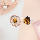 Two stickers of digital illustrated cartoon one is a flower with the bum of a bee sticking out with the word nomnomnomnomnom, the other is a sleeping bee covered in pollen with the word bzzzzzzz