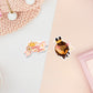 Two stickers of digital illustrated cartoon ne is a banner with a crown and flower and the words Queen Bee, the other sticker is a shy blushing bee wearing a crown.