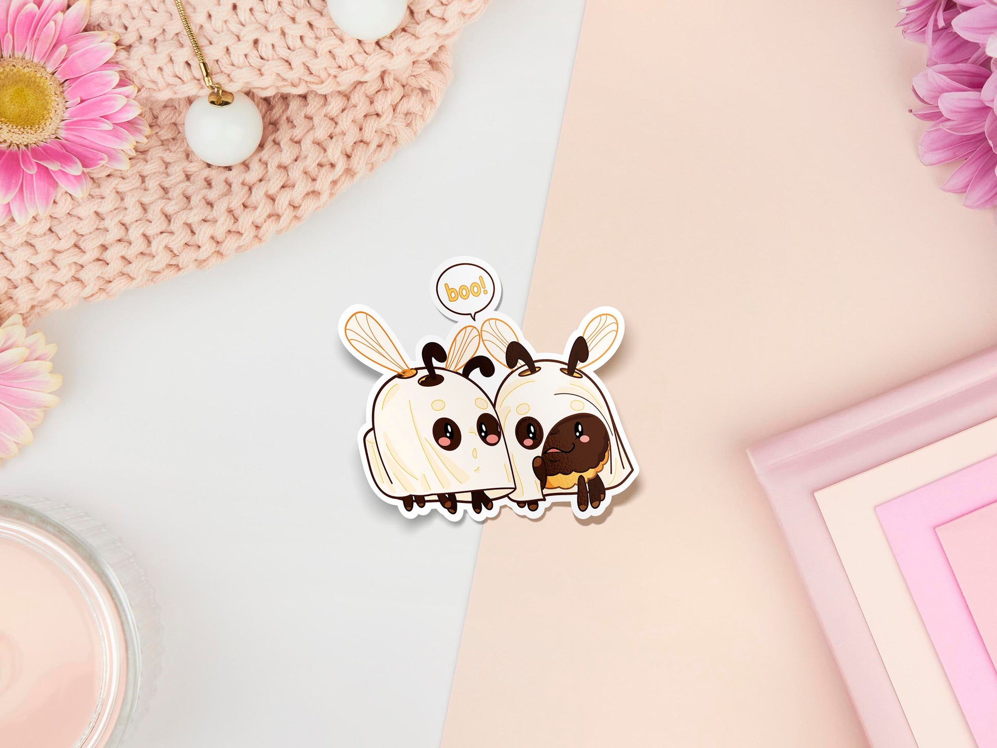 A sticker of digital illustrated cartoon of two bees dressed as ghosts with the speech bubble boo! To represent the pun Boo-bees