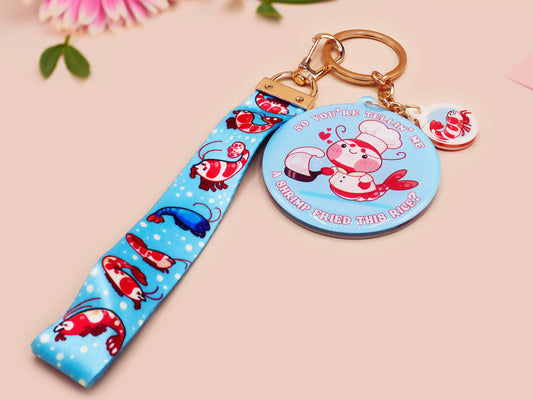 Acrylic epoxy shrimp keychain with a large acrylic charm of a a chef shrimp frying rice in a pan with the quote so you're telling me a shrimp fried this rice, a smaller charm of a cute baby shrimp and a matching blue shrimp lanyard.