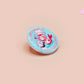 A clear acrylic pin badge with a pink heart-shaped pin back clasp. The design of the pin badge is of a cute chibi shrimp in a chefs outfit cooking with the quote So you're telling me a shrimp fried this rice?