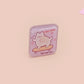 Clear acrylic pin badge with a pink heart-shaped rubber pin back clasp. The design of the pin badge is a cute chibi white cat skateboarding with the quote some people are just too cool but not me.
