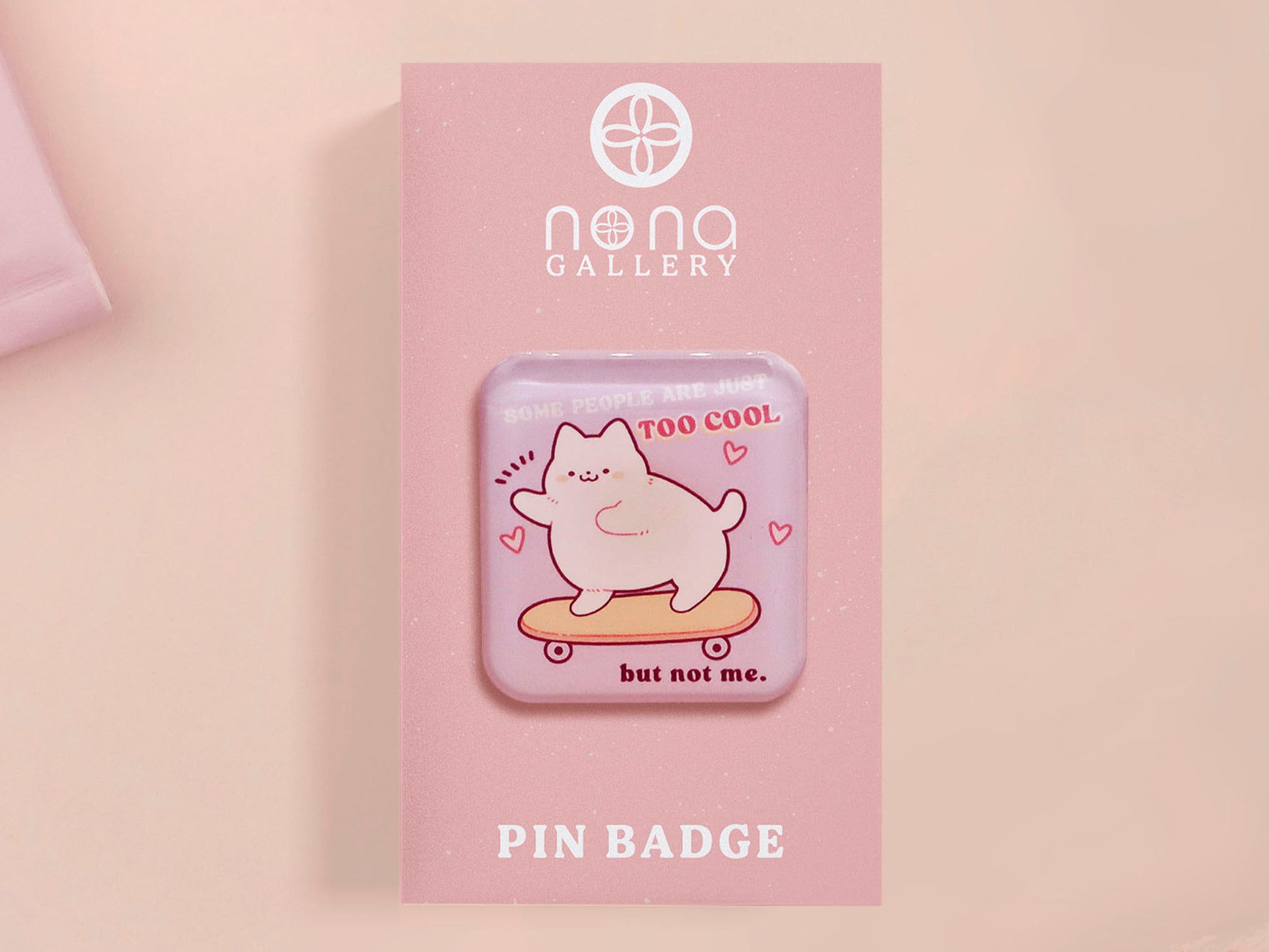 Clear acrylic pin badge with a pink heart-shaped rubber pin back clasp. The design of the pin badge is a cute chibi white cat skateboarding with the quote some people are just too cool but not me.