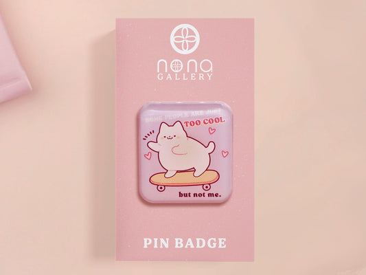 Clear acrylic pin badge with a pink heart-shaped rubber pin back clasp. The design of the pin badge is a cute chibi white cat skateboarding with the quote some people are just too cool but not me.